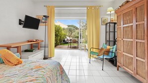 A room with a bed, a desk, a TV, a chair, a wardrobe, and a view of the outside.
