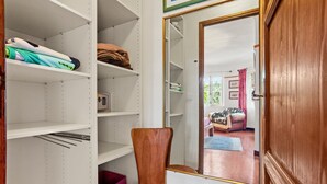 Une pièce avec une chaise en bois, un miroir et des étagères où sont pliés des vêtements.