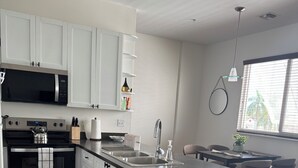 Une cuisine moderne avec des armoires blanches, un four à micro-ondes encastré, une cuisinière et un grand îlot central doté d’un évier.