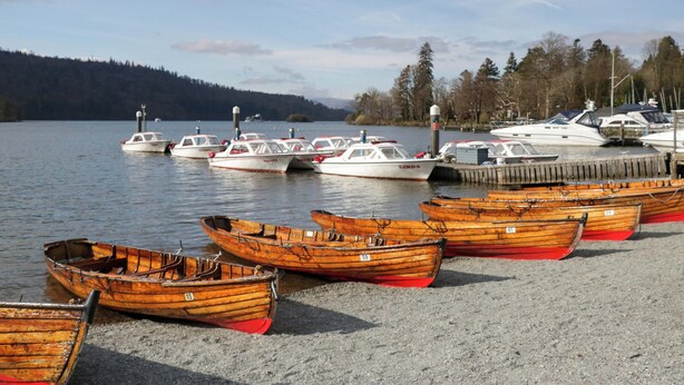 A marina with several wooden boats docked and a few white motorboats. - The Studio (Windermere)