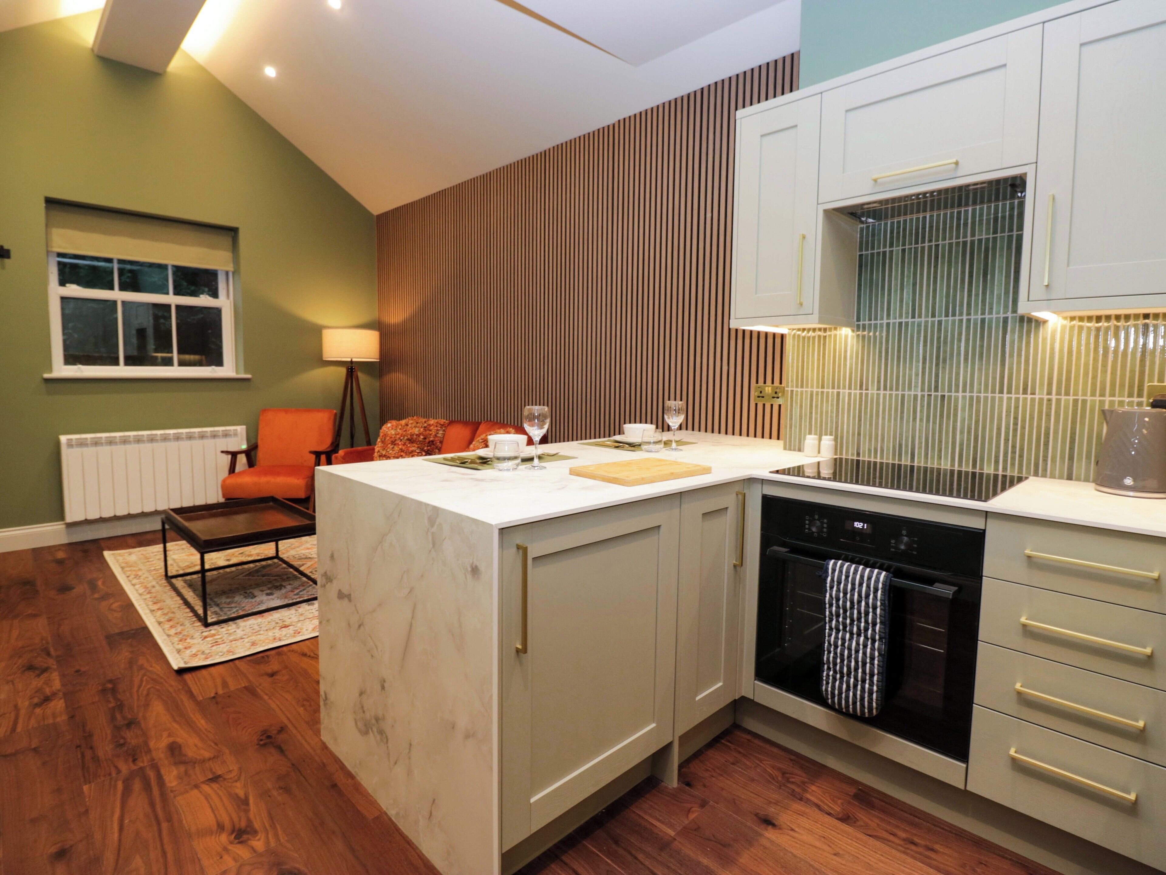 A modern kitchen with a marble island, white cabinets, and a built-in oven.