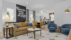 Een moderne woonkamer met een bank, stoelen, een salontafel en een keuken op de achtergrond.