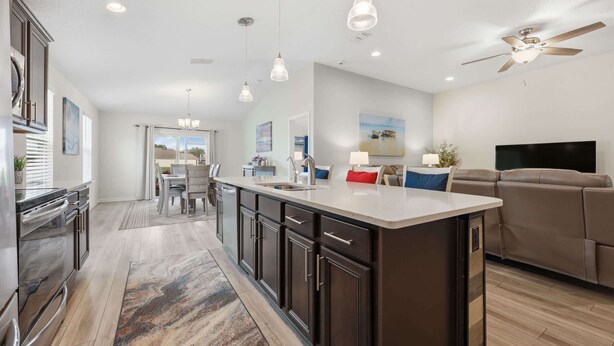A modern kitchen with dark cabinets, a large island, pendant lights, and a ceiling fan. - Serenity by the Sea - For 6 (St. Augustine)