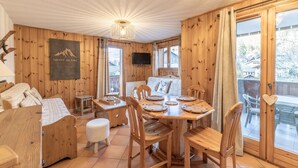 Un interior de madera con una mesa de comedor, sillas, un sofá y un televisor.