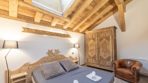 A bedroom with a wooden headboard, a large wardrobe, a leather armchair, and a skylight. - Apartment 'Morillon – New – 2 min from the slopes' with mountain view, private terrace (Morillon)