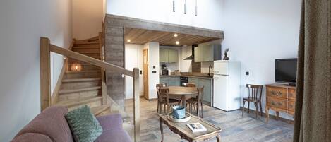 Un salon avec un escalier, un coin repas et une cuisine.