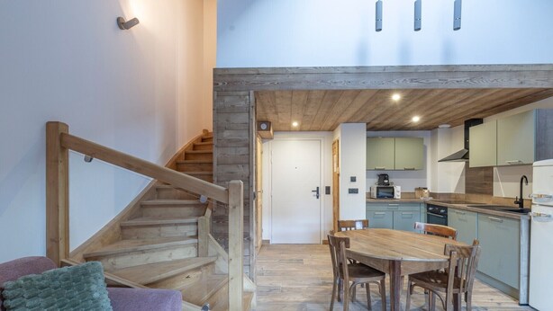 Une cuisine moderne avec des meubles en bois, un coin repas avec une table et des chaises en bois, et un escalier avec des rampes en bois.