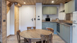 Une cuisine compacte avec une table et des chaises en bois, un four à micro-ondes et un réfrigérateur.
