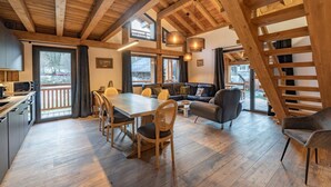 Un vaste espace de vie doté d’un plafond en bois, d’une table à manger et d’un canapé.
