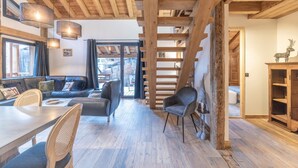 Un intérieur moderne avec un plafond en bois, un coin repas comprenant une table et des chaises, un canapé et un escalier.
