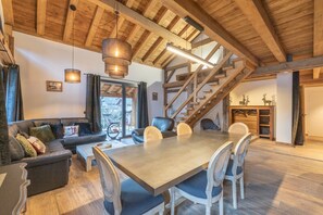 Una zona de estar acogedora con sofá, mesa de comedor, sillas y una escalera.