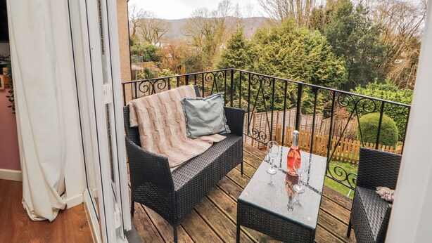 Un balcon avec un canapé, une table et une bouteille de vin.
