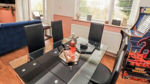 Een eetruimte met een glazen tafel, stoelen, een klok en uitzicht op de omgeving.