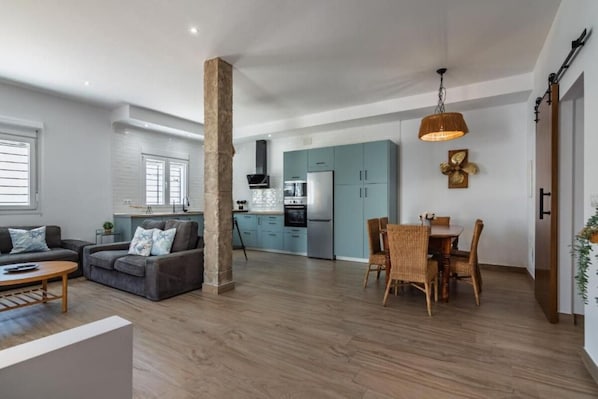 A modern living space with a sofa, dining table, and kitchen area.