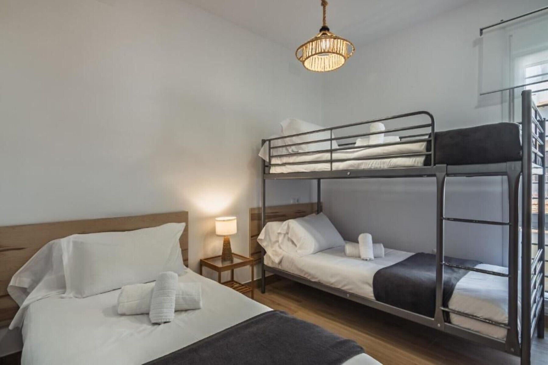 Een slaapkamer met stapelbed, nachtkastje, lamp en hanglamp.