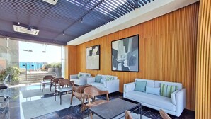 A modern lobby with a white sofa, brown chairs, and a marble floor. - Luxury loft Roma Norte with pool, gym, AC & cowork (Ciudad de México)