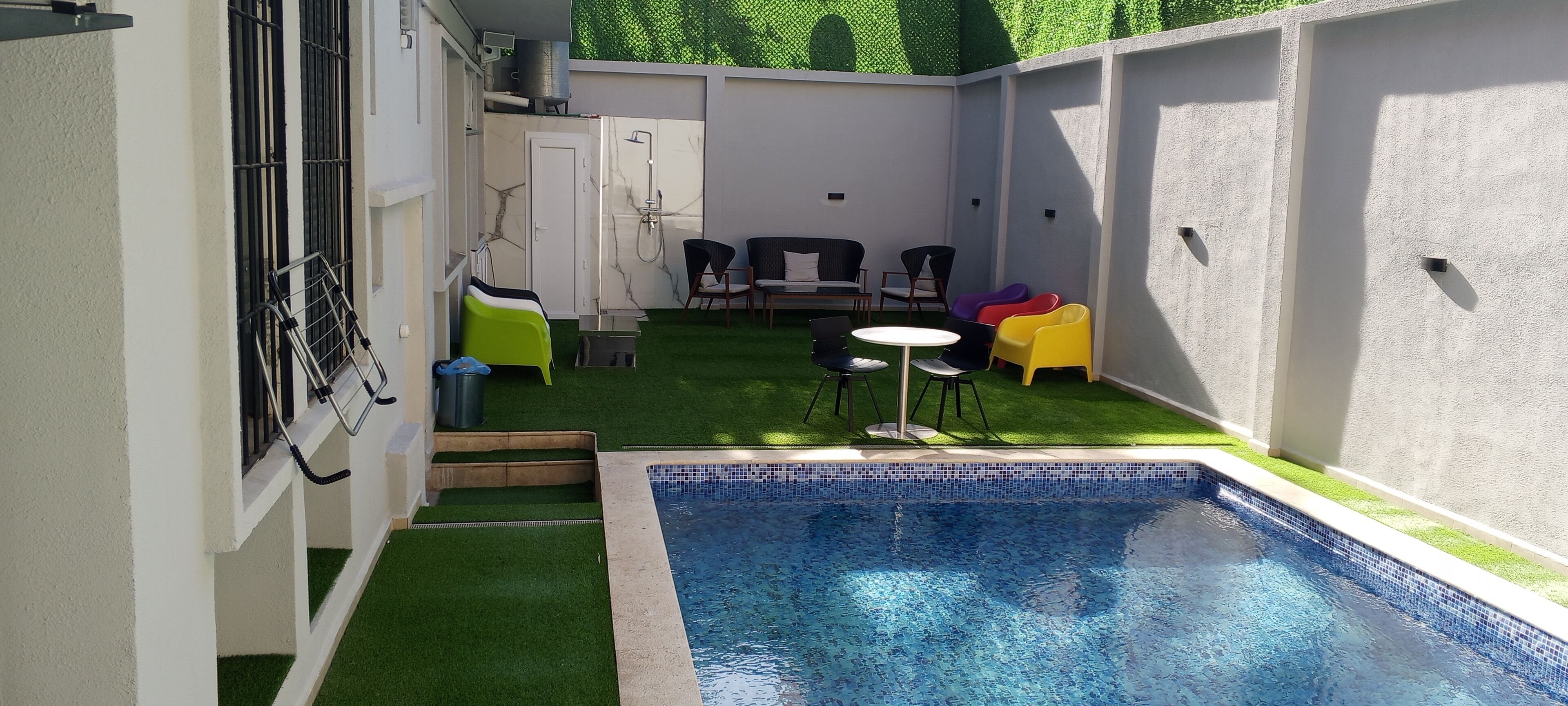 A small backyard with a swimming pool, artificial grass, and outdoor furniture.