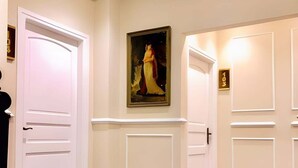 Un pasillo de hotel con puertas blancas, alfombra roja y un cuadro enmarcado en la pared.
