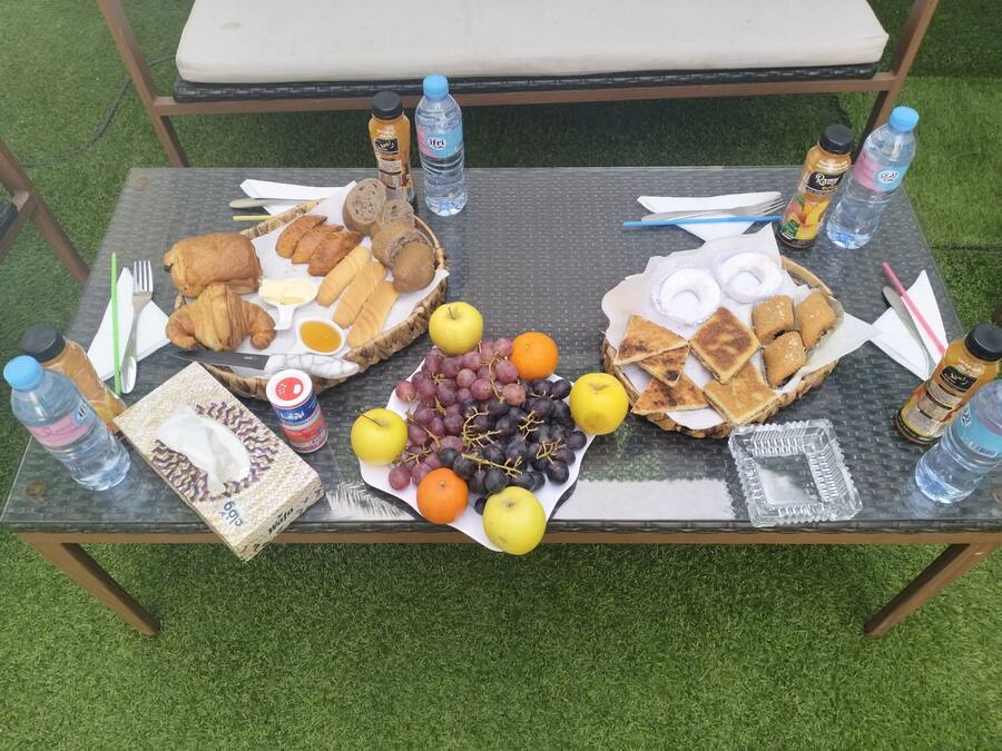 Una mesa al aire libre con alimentos, incluyendo pan, frutas y salsas.