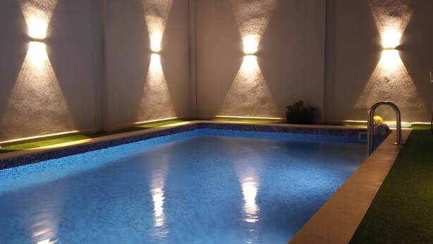 Una piscina interior con agua cristalina, rodeada de paredes con iluminación integrada.