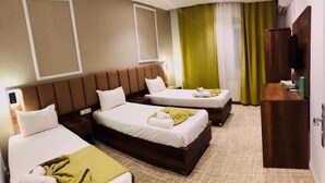 Habitación de hotel con dos camas, cabecero de madera, televisión y escritorio.