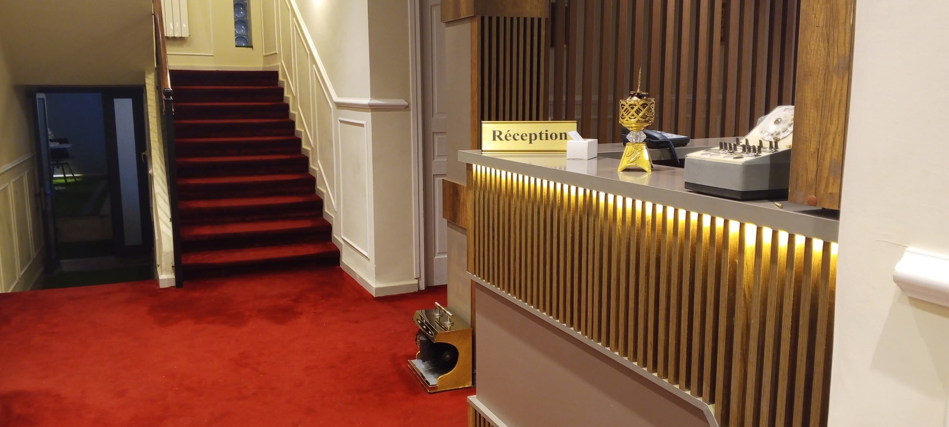 A reception area with a red carpet, a reception desk, and a staircase leading to another floor.