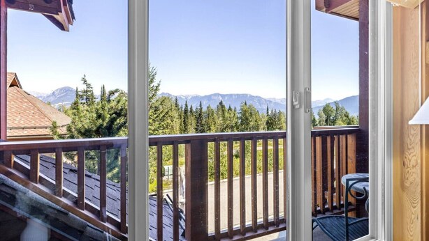 Un balcon avec vue sur les montagnes et les arbres.