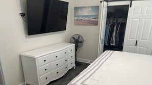 A bedroom with a bed, a dresser, a TV, a fan, and a closet. - Perfect 3-bedroom house with AC in Fort Myers Beach (Fort Myers Beach)
