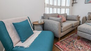 A cozy living room with a teal sofa, grey armchairs, and a patterned rug. - Betty's Buoy (Weymouth)
