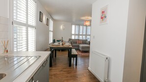 A modern kitchen with a large island, a dining area with a table set for four, and a cozy living room with a sofa and a fireplace. - Betty's Buoy (Weymouth)