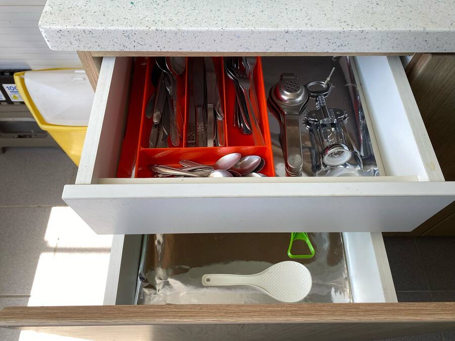 Un cajón con utensilios y una cuchara.