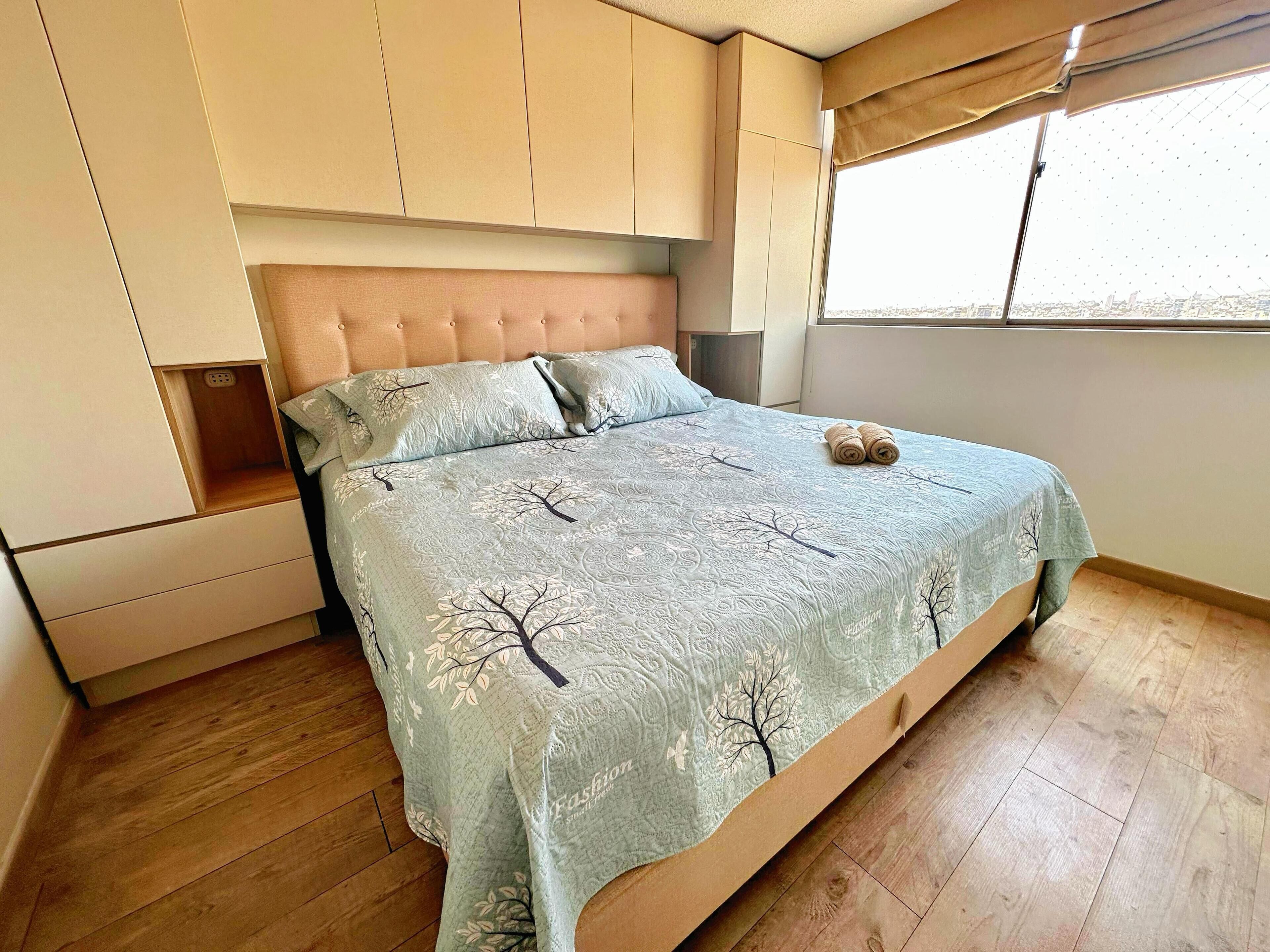 Un dormitorio con cama, armario empotrado y ventana.