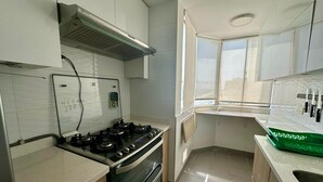 Μια κουζίνα με γκαζιέρα, φούρνο κα ι ένα παράθυρο με ωραία θέα.