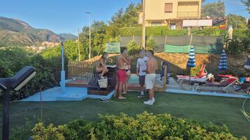 Zona de piscina con muelle de madera, sillas de descanso y sombrillas.