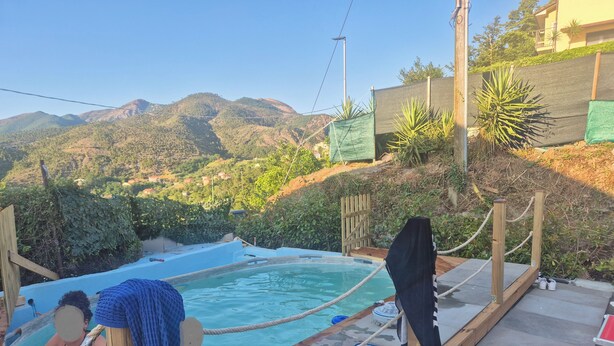 Ein Poolbereich mit Holzterrasse, Seilen und Blick auf die Berge.