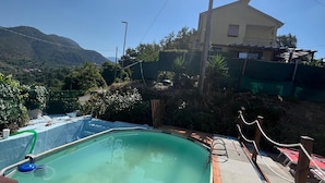 Ein Schwimmbecken mit Holzterrasse, umgeben von einem Zaun und einer Seilsperre.