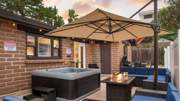 Een achtertuin met een hottub, terras en vuurkorf.