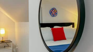 Ein Zimmer mit einem Bett, einer Nachttischlampe und einem Spiegel auf einem Holztisch.