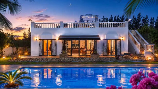 Una casa moderna con piscina, ventanas amplias y un porche cubierto.