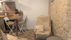 Ein gemütliches Zimmer mit Fischgrätparkett, einer Steinwand, einem runden Tisch und zwei beigen Stühlen.