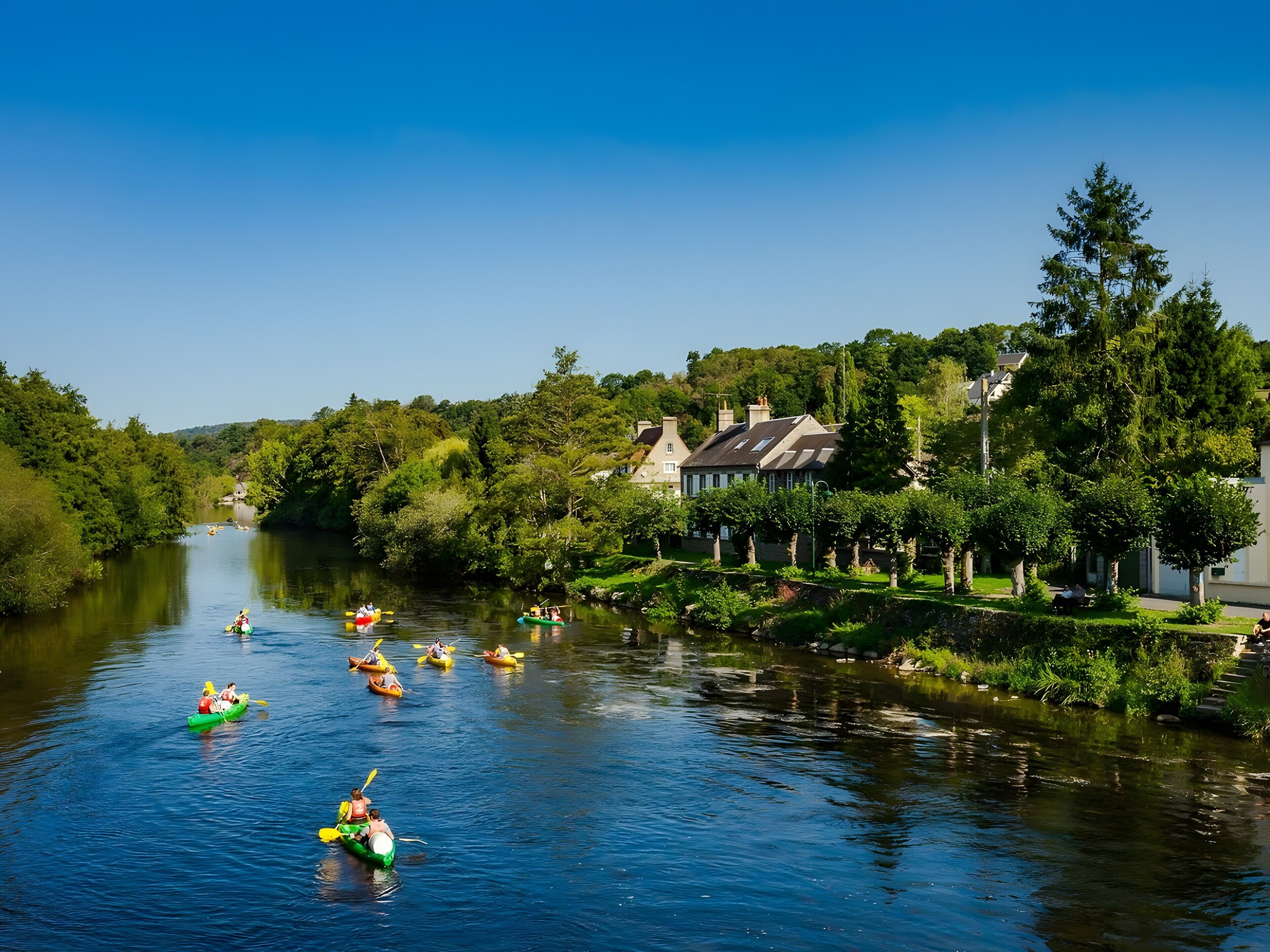 Une rivière où l’on peut faire du kayak, avec des maisons et des arbres sur ses rives.