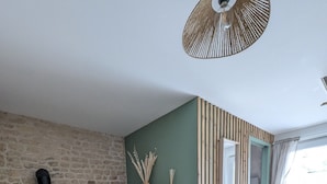 Ein Wohnzimmer mit einer Steinsäule, einem hölzernen Bücherregal, einem Sofa, einem kleinen Tisch und einem Kamin.