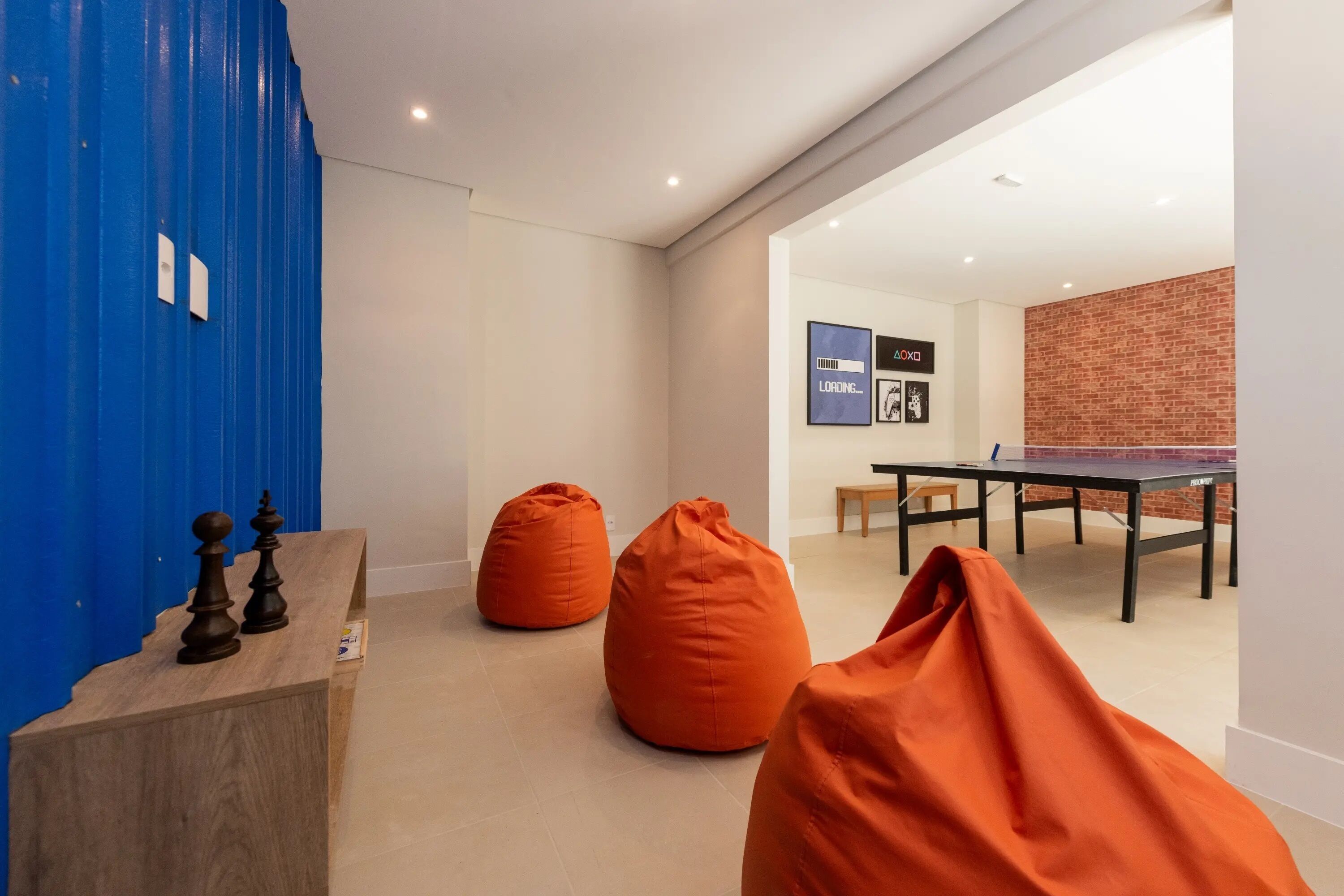 Ein modernes Zimmer mit einem Holztisch, zwei orangen Sitzsäcken und einem Tischtennistisch.