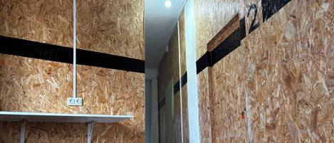 A narrow hallway with wooden paneling, a white ceiling, and a black metal stool.