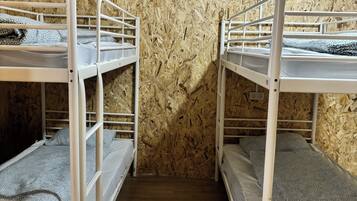 Een kamer met stapelbedden tegen een houten wand, een houten vloer en een stopcontact op de muur.