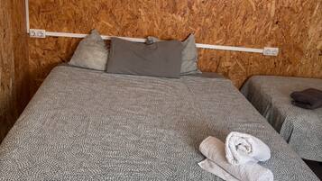 Una habitación con cama, mesita de noche y una pared cubierta de virutas de madera.