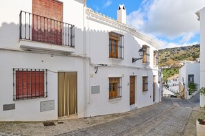 A narrow cobblestone street flanked by white buildings with balconies, wooden doors, and barred windows. - Casa Rural Martemma: Mountain Views, Private Pool, and Air Conditioning (Zuheros)