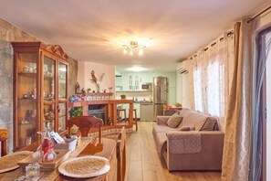 A living room with a dining table, sofa, and kitchen in the background. - Casa Rural Martemma: Mountain Views, Private Pool, and Air Conditioning (Zuheros)