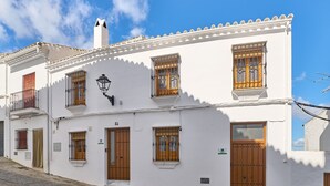 Un edificio bianco con numerose finestre e porte, una strada acciottolata e un cielo sereno.