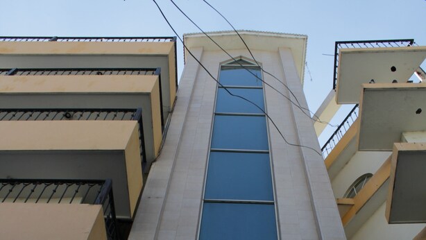 A multi-story building with a central glass facade and balconies. - Hotel El Baron (León)